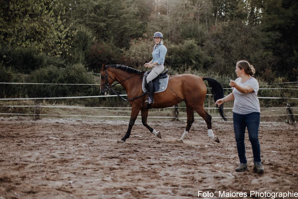 Reiterin auf Pferd wird von Trainerin eingewiesen